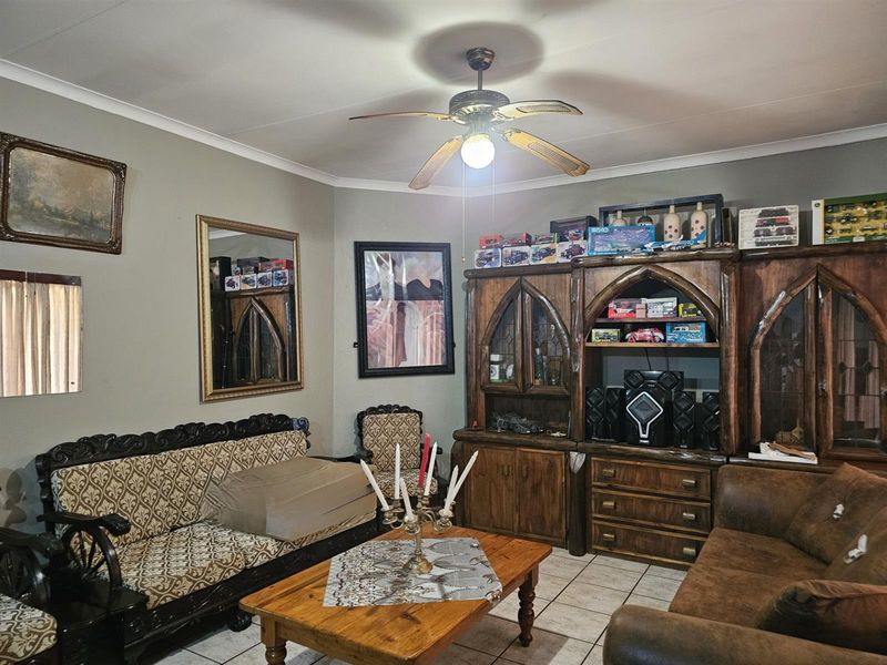 A living room featuring tiled flooring, a central ceiling fan, and coving, providing a functional space for relaxation.