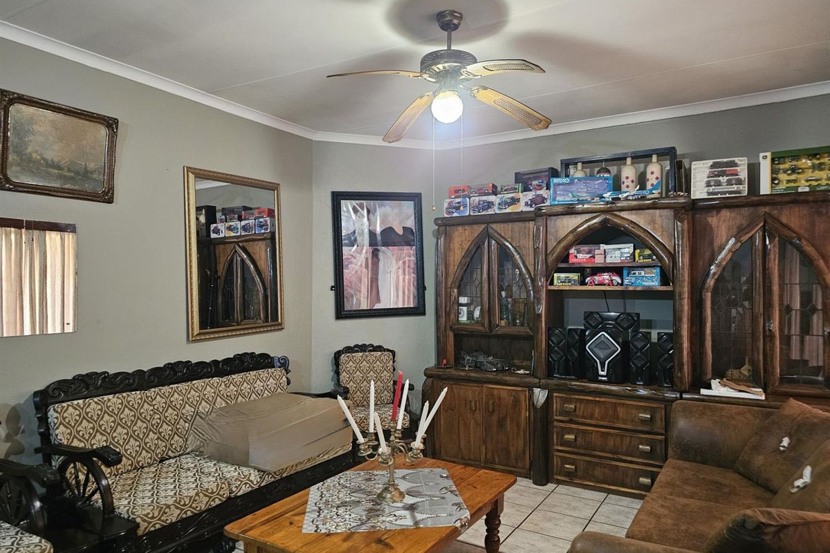 A living room featuring tiled flooring, a central ceiling fan, and coving, providing a functional space for relaxation.