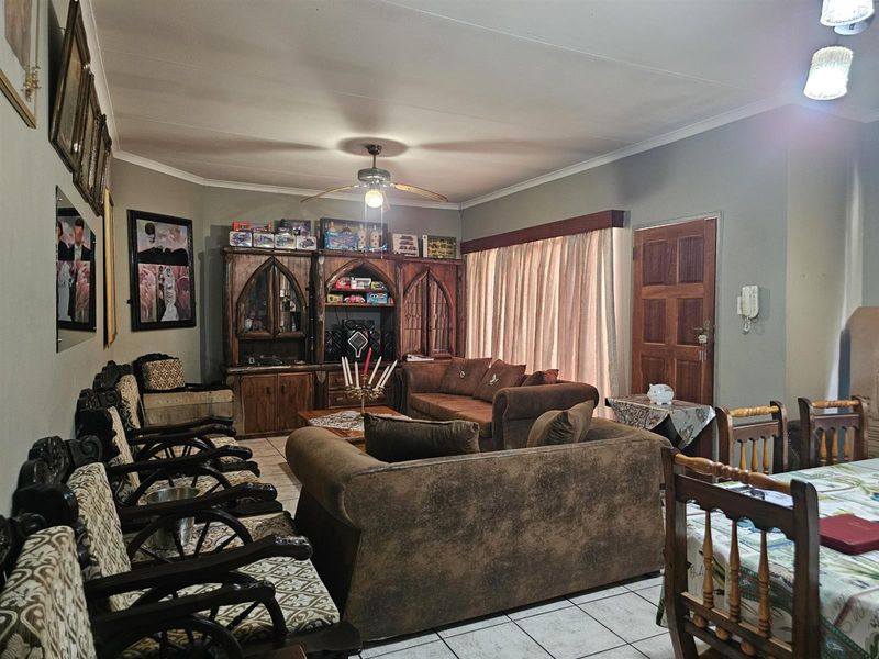Open plan living and dining area featuring tiled flooring, a ceiling fan, and direct access to an exterior door.