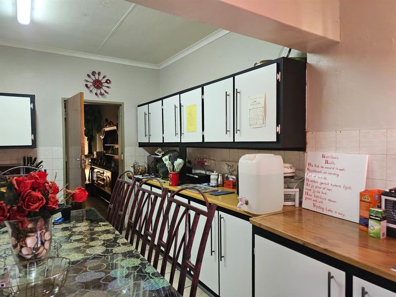 A functional kitchen featuring built-in cabinetry, laminate countertops, and a tiled backsplash, offering a practical layout for daily meal preparation.
