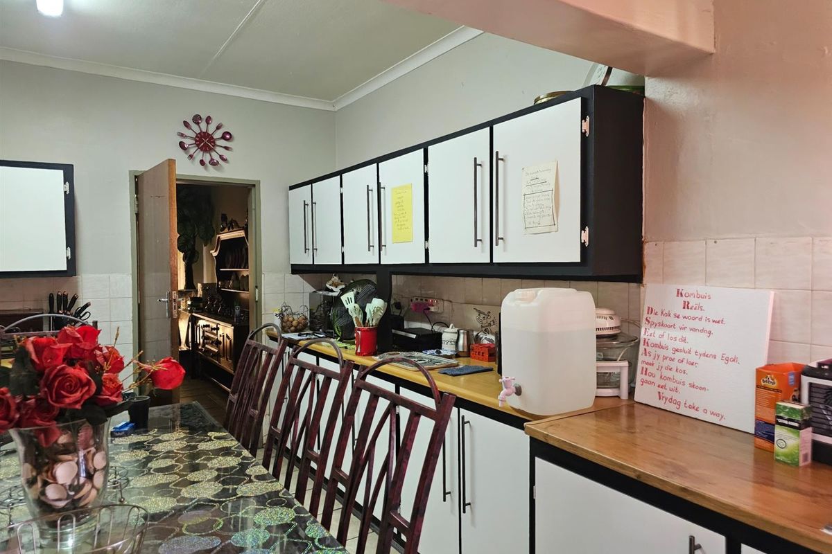 A functional kitchen featuring built-in cabinetry, laminate countertops, and a tiled backsplash, offering a practical layout for daily meal preparation.
