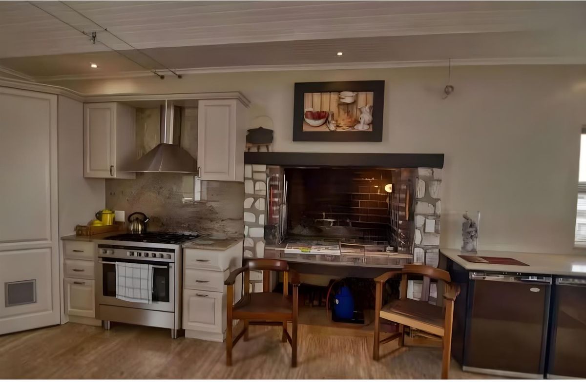 Kitchen featuring built-in cabinetry, stainless steel gas stove with extractor fan, and a rustic stone-clad indoor fireplace.