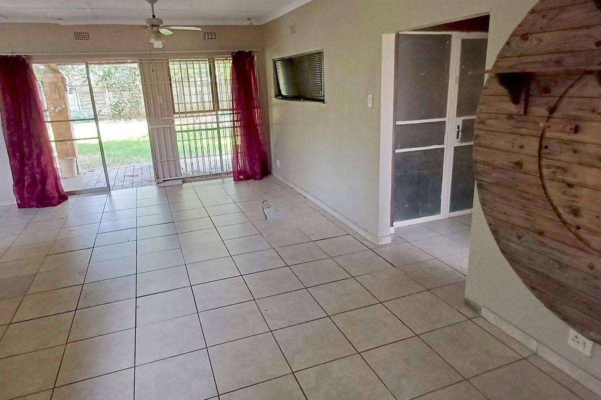 Spacious living area featuring tiled flooring, a ceiling fan, and sliding glass doors providing access to the rear garden.