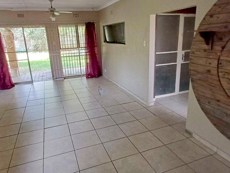 Spacious living area featuring tiled flooring, a ceiling fan, and sliding glass doors providing access to the rear garden.