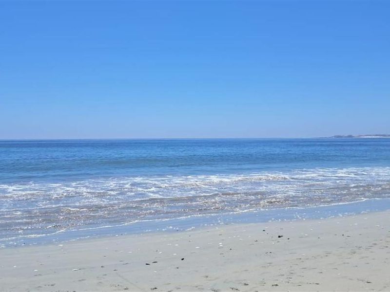 A scenic view of the ocean and sandy beach, highlighting the property's coastal location and natural surroundings.