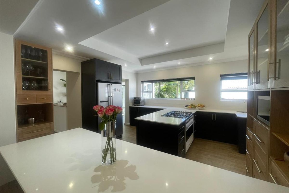 Modern kitchen featuring dark cabinetry, a central island with a built-in gas hob, stone countertops, and recessed ceiling lighting.