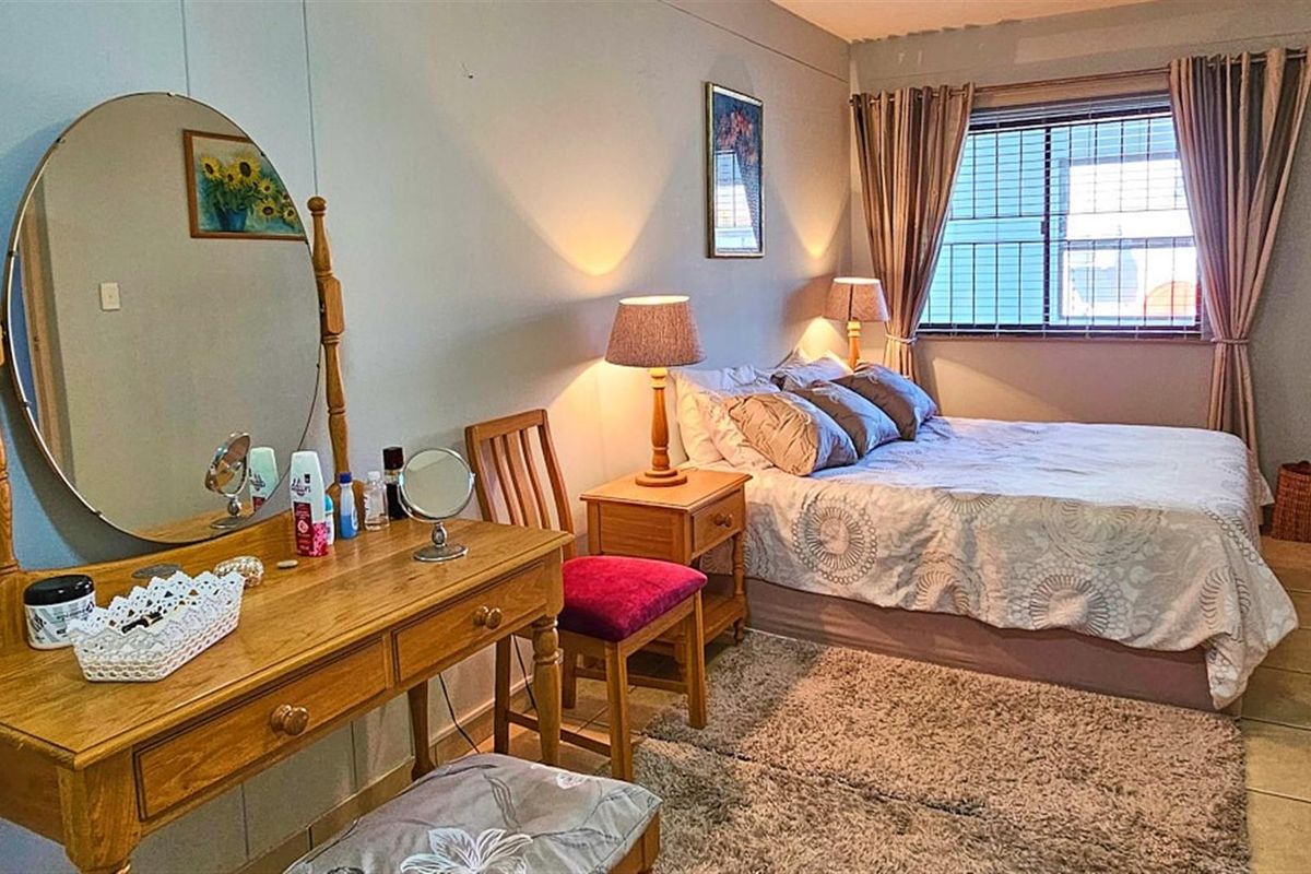 A bedroom featuring tiled flooring and a window with security bars, providing a functional and comfortable living space.