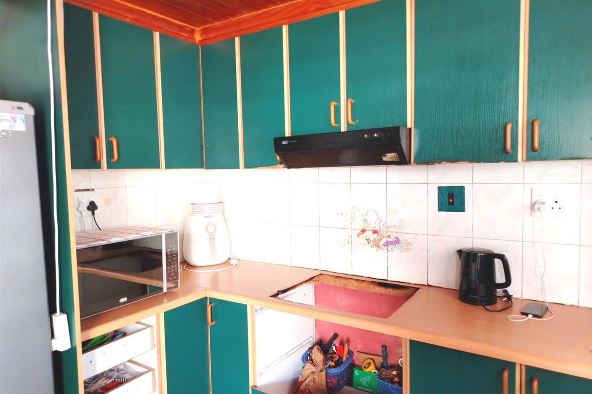 A kitchen featuring green cabinetry, timber ceiling, and tiled backsplash, currently requiring a new cooktop installation and general cosmetic updates.
