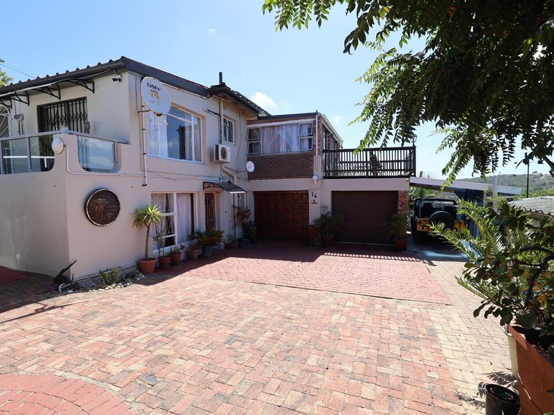 Front exterior view of a multi-level residential property featuring a paved driveway, integrated garage, and an elevated balcony area.