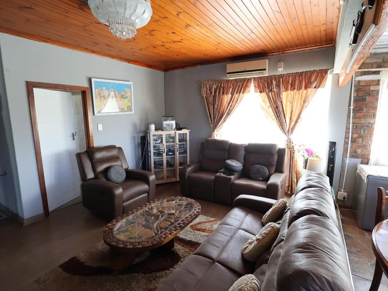 A living room featuring a timber-clad ceiling, split-system air conditioning unit, and tiled flooring, providing a functional and comfortable living space.