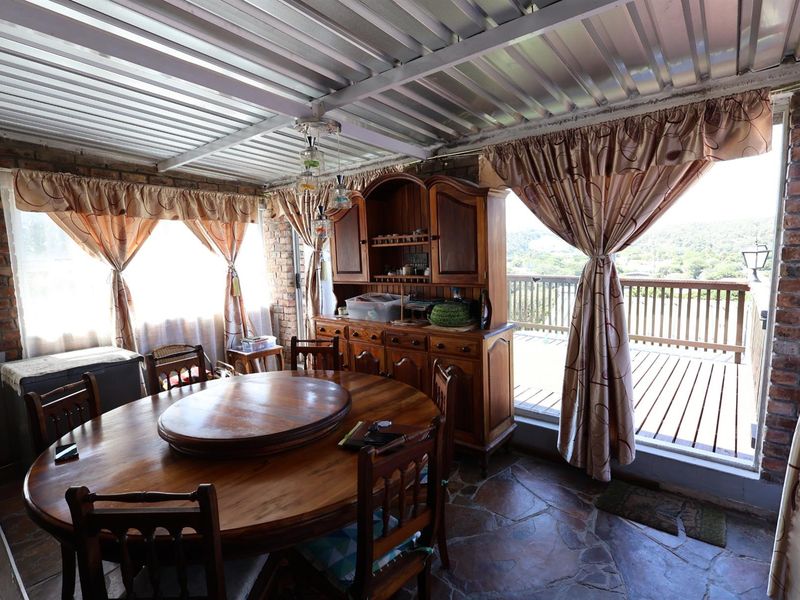 Dining area featuring rustic exposed brick walls, stone flooring, and a corrugated metal ceiling, with direct access to an outdoor deck.