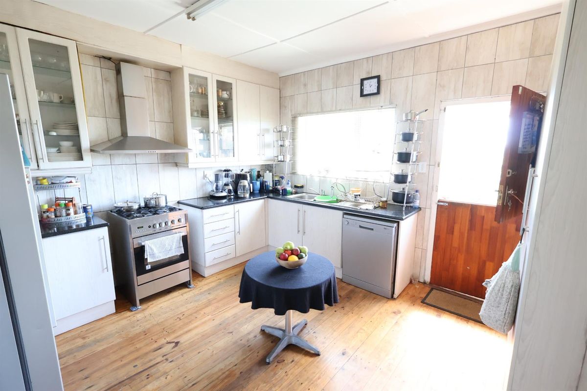 Functional kitchen featuring white cabinetry, dark countertops, stainless steel extractor fan, gas stove, and direct access to the exterior.