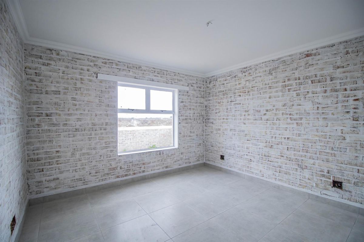 A bright, vacant bedroom featuring modern light-toned tiled flooring and distinctive whitewashed brick-style feature walls with a large window.