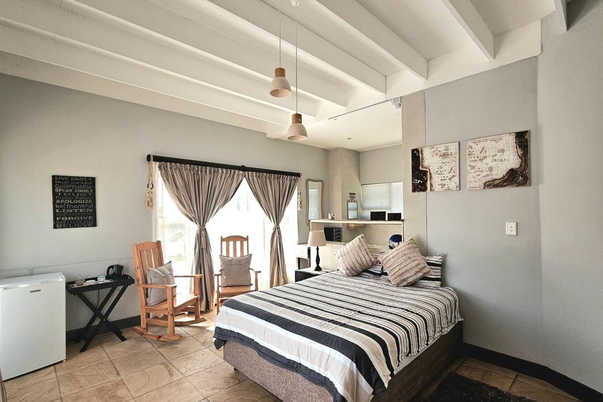 A bedroom featuring exposed white timber ceiling beams, tiled flooring, and built-in cabinetry, offering a comfortable and functional living space.