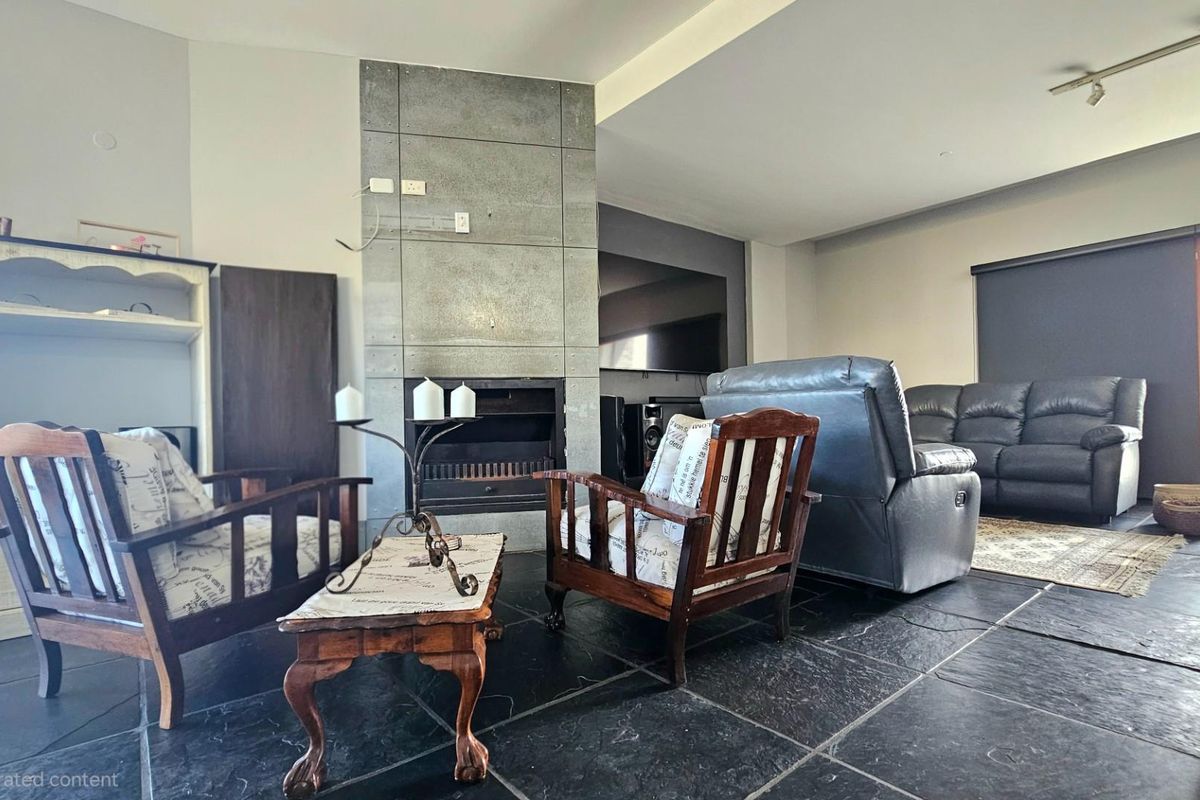 Spacious living room featuring a central fireplace with a modern concrete-style surround and dark stone flooring throughout.