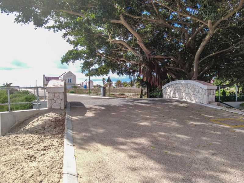 A paved bridge structure featuring stone masonry pillars and metal railings, set within a landscaped area with mature trees.