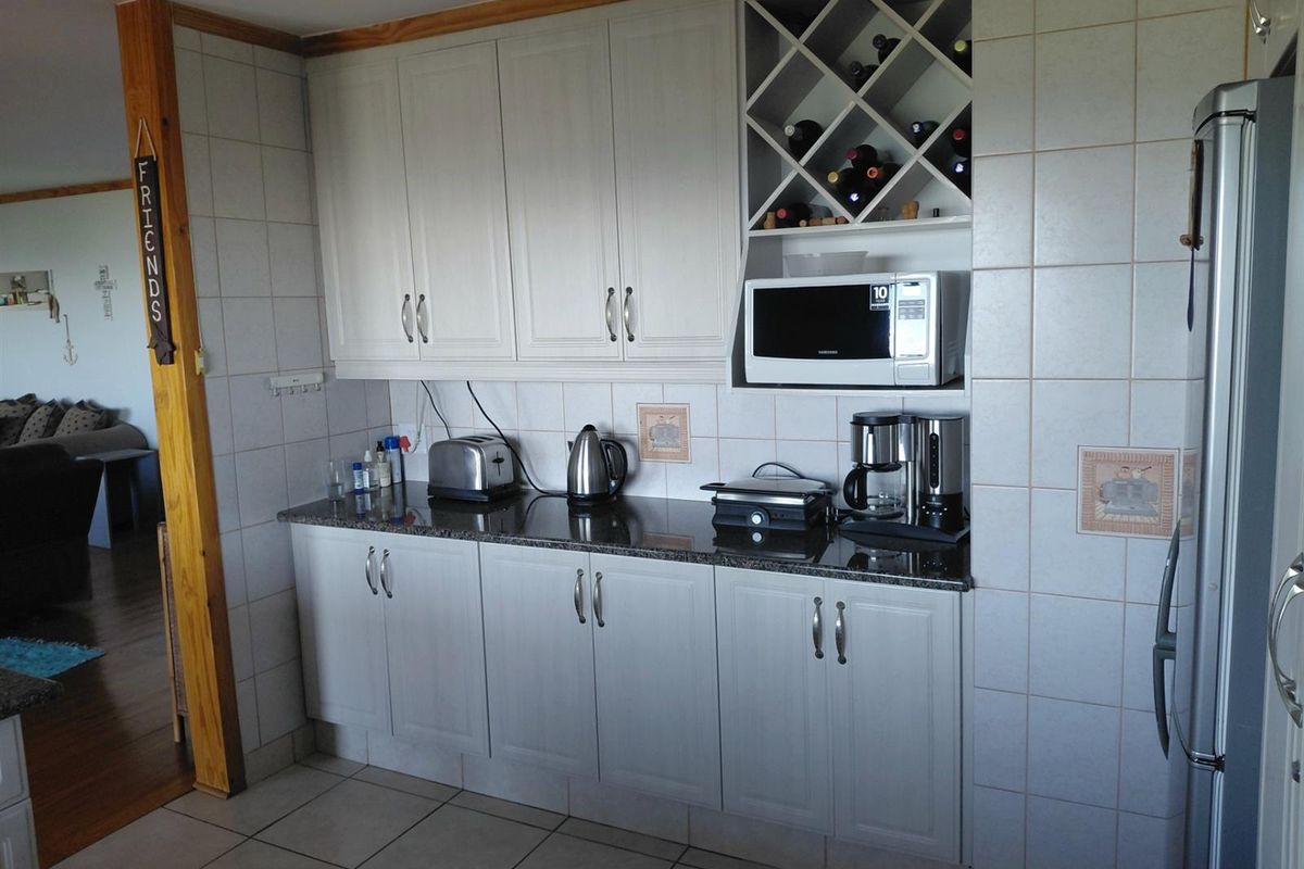 A functional kitchen area featuring light-toned cabinetry, granite countertops, tiled walls, and a built-in wine rack, providing efficient storage and workspace.