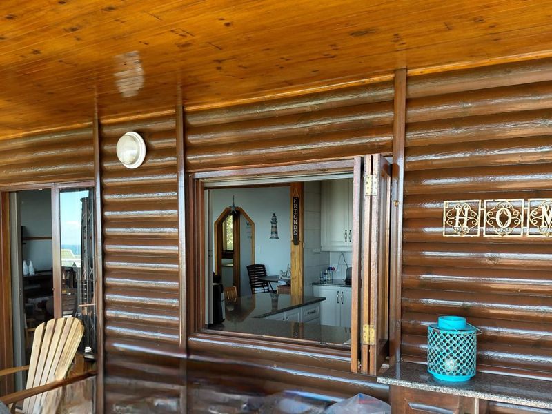 Covered patio area featuring timber log-style wall cladding, a built-in serving counter, and direct access to the kitchen through folding windows.