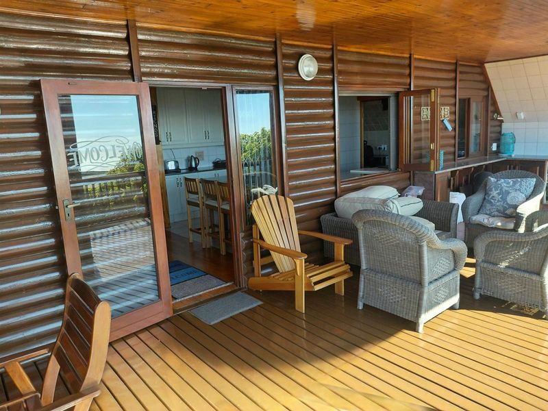 Covered wooden deck featuring timber wall cladding and direct access to the kitchen area through glass doors and a serving window.