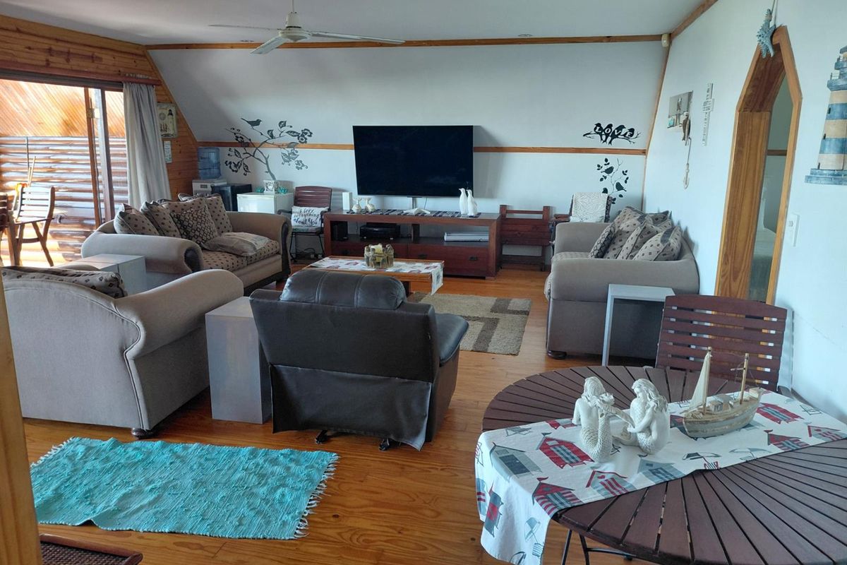 Spacious living area featuring timber flooring, a vaulted ceiling with a fan, and sliding door access to an outdoor patio.