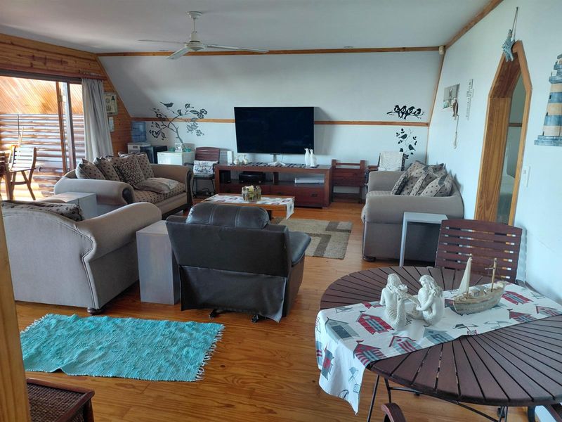 Spacious living area featuring timber flooring, a vaulted ceiling with a fan, and sliding door access to an outdoor patio.