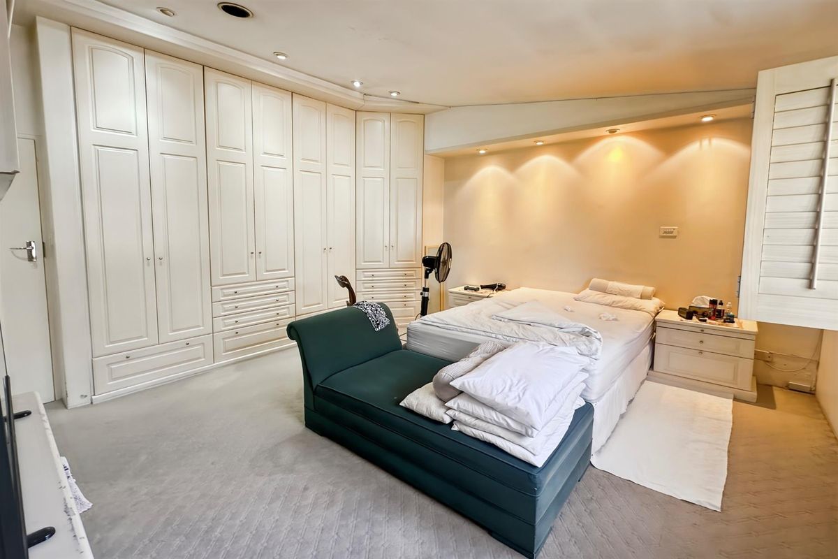 Spacious bedroom featuring extensive built-in cabinetry, recessed ceiling lighting, and neutral carpeting.