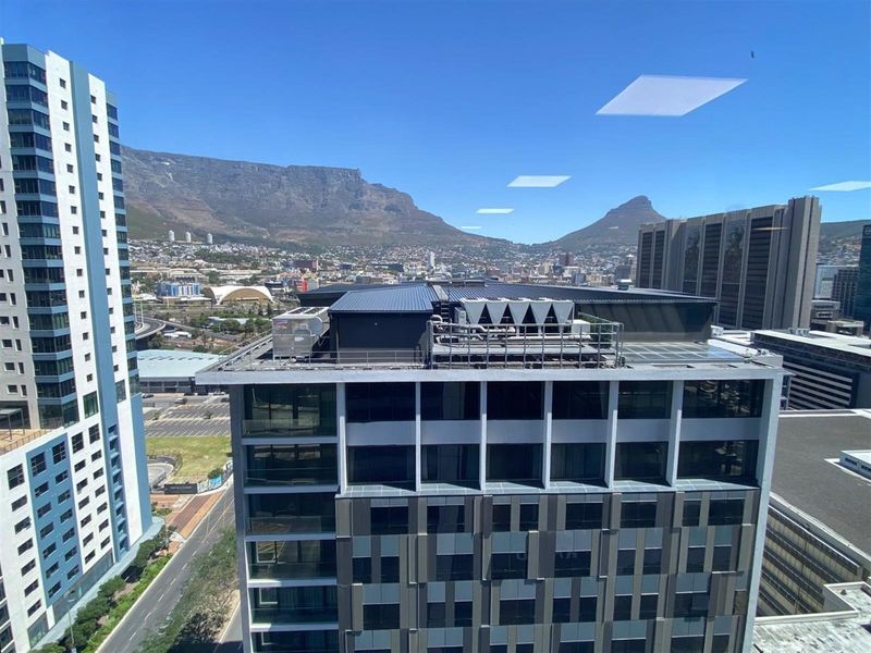 Elevated city view overlooking surrounding high-rise office buildings and the mountain range in the distance.