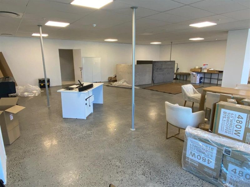 Spacious open-plan office area featuring polished concrete flooring, recessed ceiling lighting, and structural support columns.