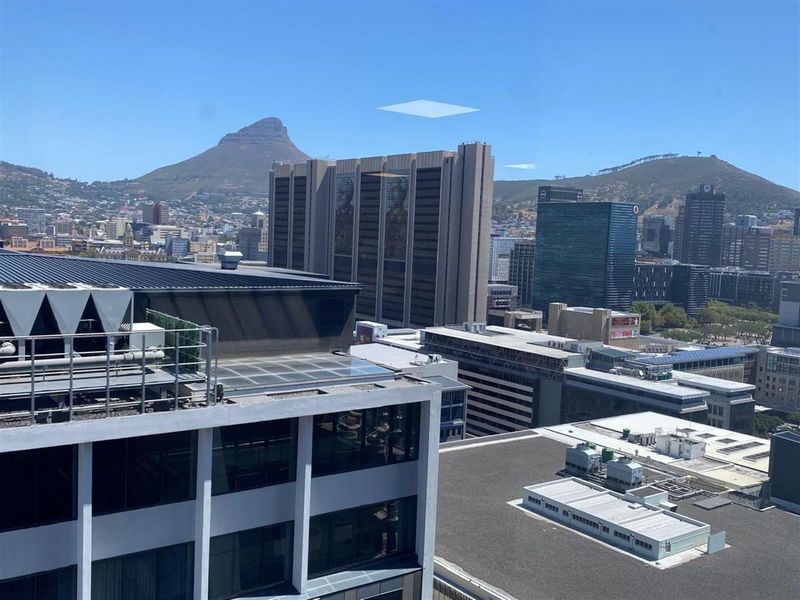 Elevated city view overlooking surrounding office buildings and urban landscape with mountain backdrop.