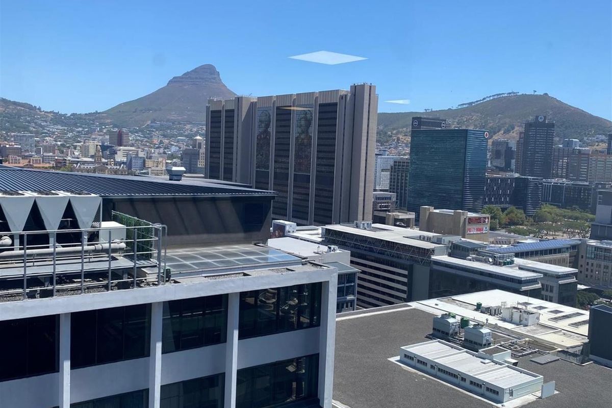 Elevated city view overlooking surrounding office buildings and urban landscape with mountain backdrop.