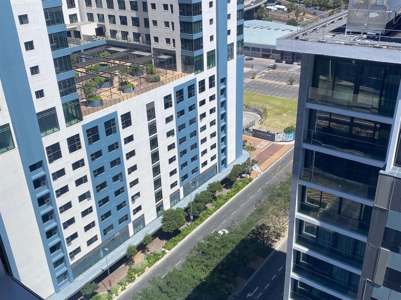 An elevated aerial view overlooking a modern urban office complex, surrounding streets, and landscaped rooftop terrace areas.
