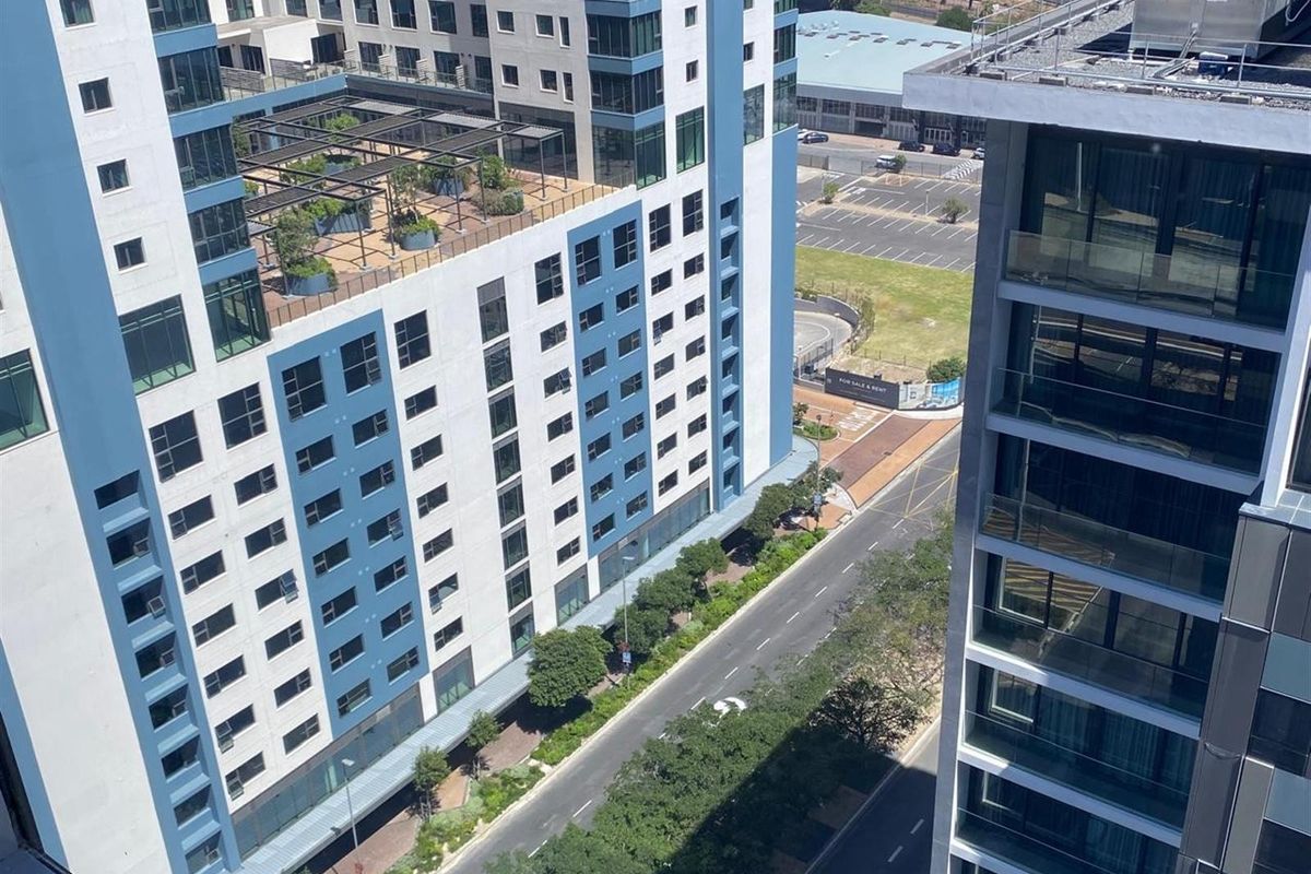 An elevated aerial view overlooking a modern urban office complex, surrounding streets, and landscaped rooftop terrace areas.