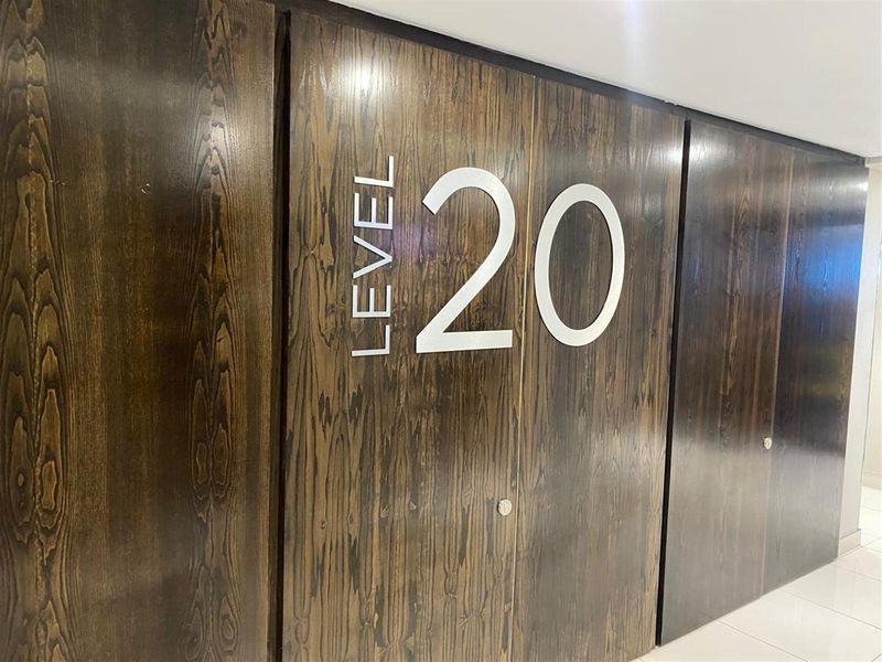 A modern office hallway featuring dark wood-paneled walls with clear level signage.