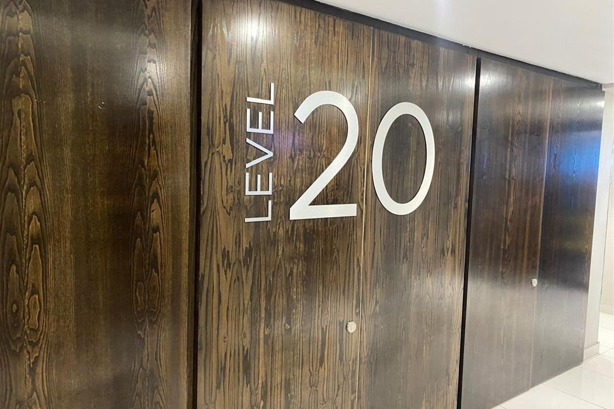A modern office hallway featuring dark wood-paneled walls with clear level signage.
