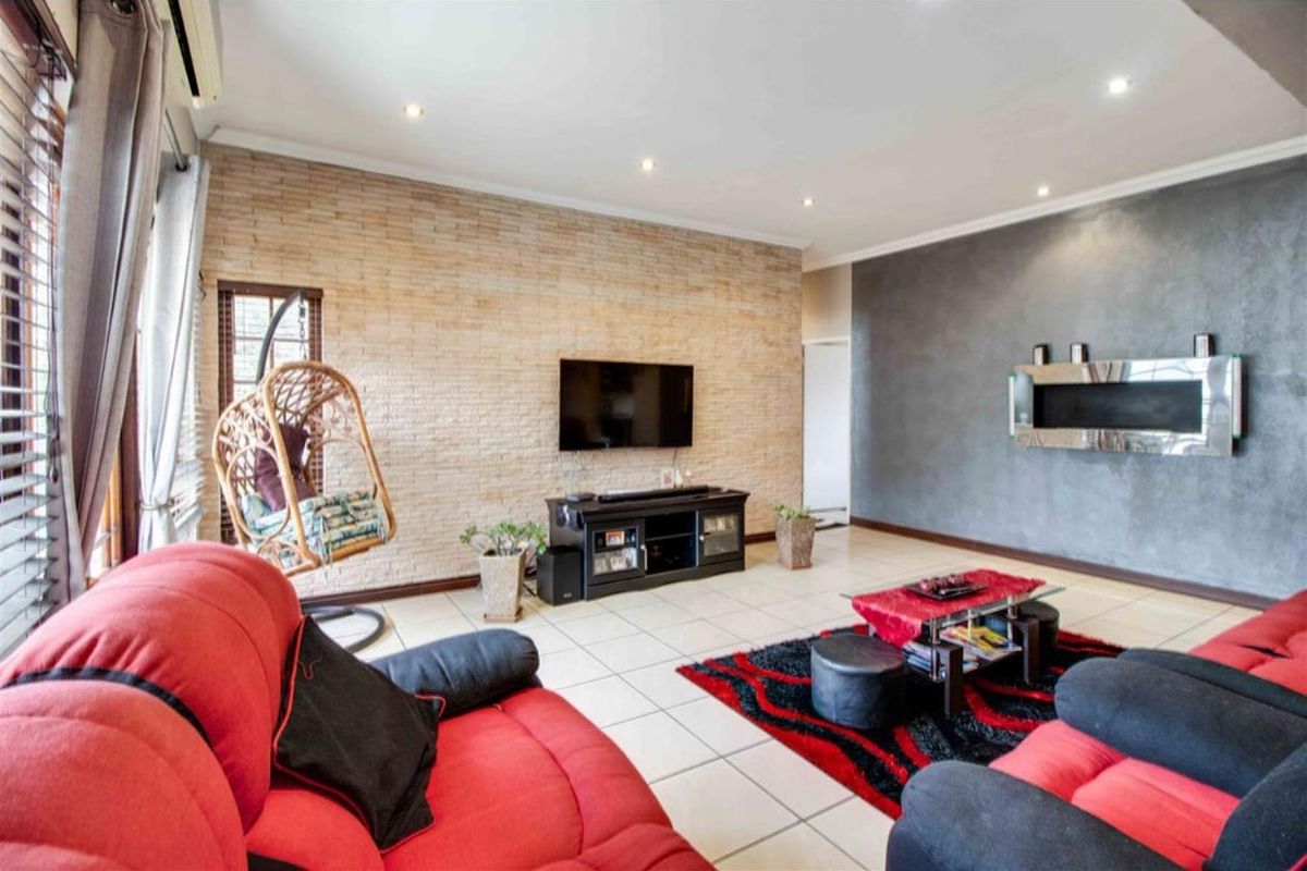 Spacious living room featuring a textured stone feature wall, a modern built-in fireplace, tiled flooring, and recessed ceiling lighting.
