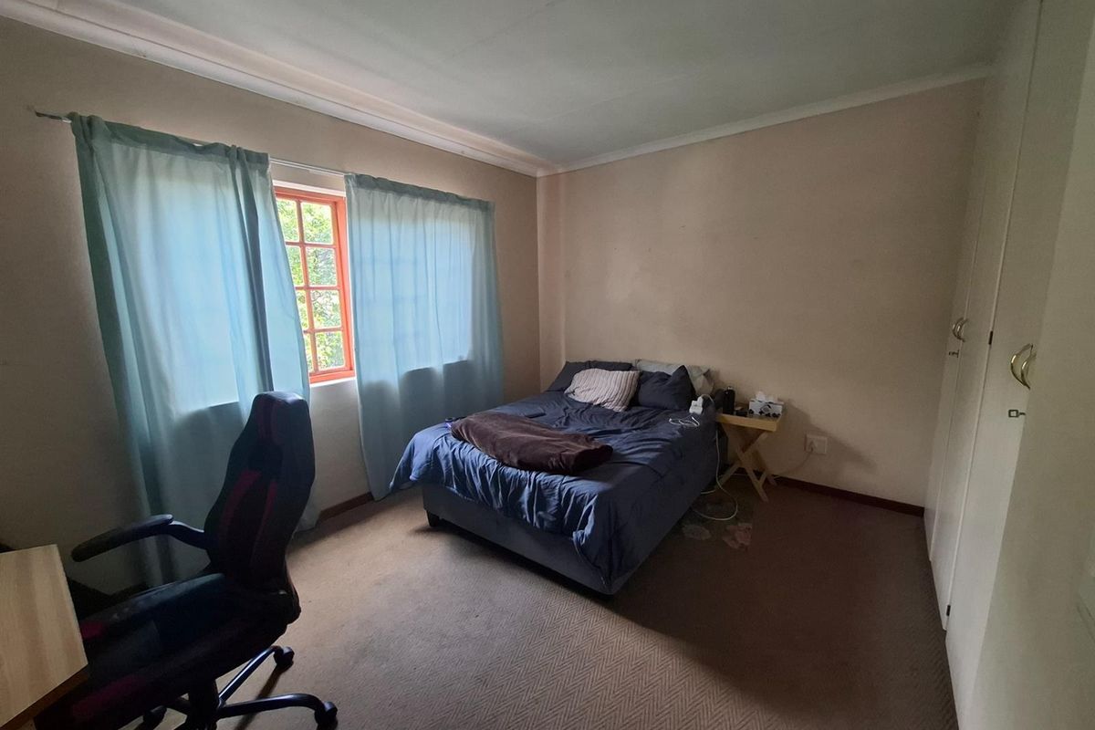 A standard bedroom featuring built-in cupboards, carpeted flooring, and a window with natural light.