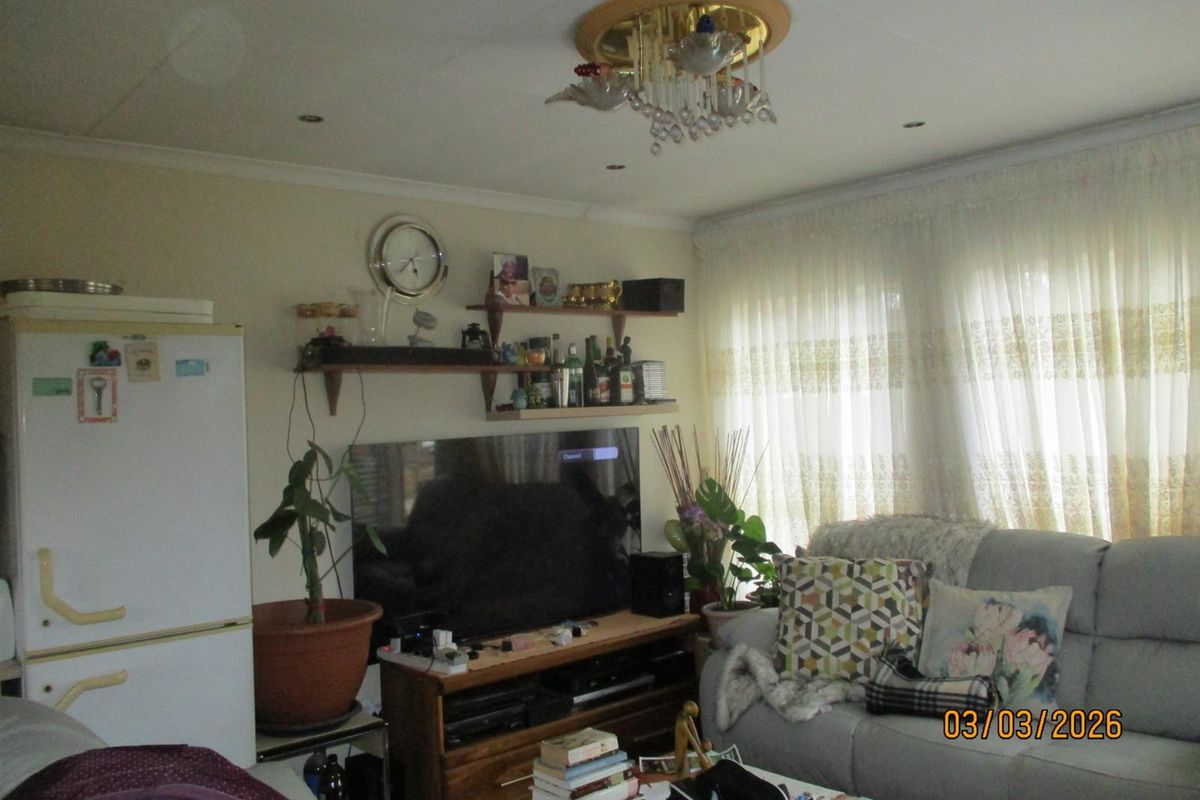 A living room featuring coved cornicing, recessed downlights, and a decorative central light fixture.