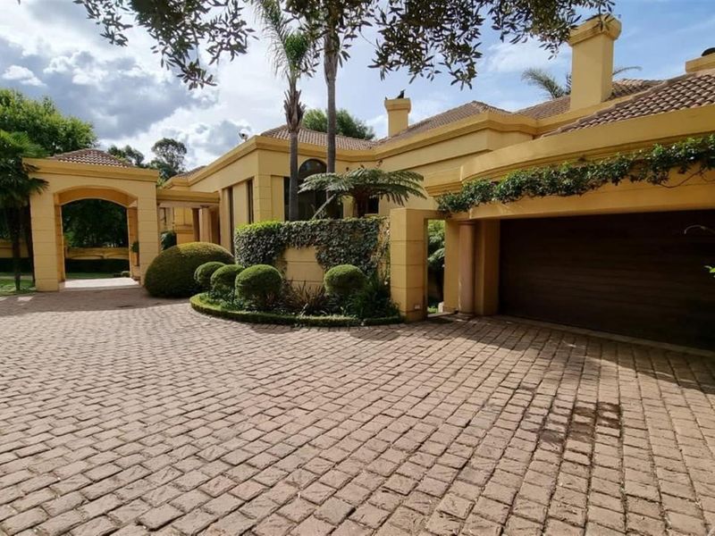 A well-maintained front exterior view of the house featuring a paved driveway, covered entrance, and integrated garage with mature landscaping.