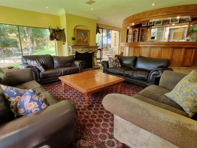 Spacious living area featuring a built-in wooden bar, a decorative stone fireplace, and large sliding glass doors providing access to the garden.