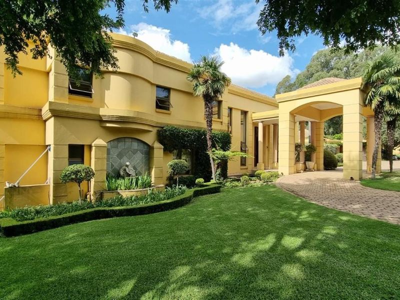 A grand front elevation of a yellow-toned residence featuring a covered porte-cochère entrance, manicured lawn, and a decorative water feature.