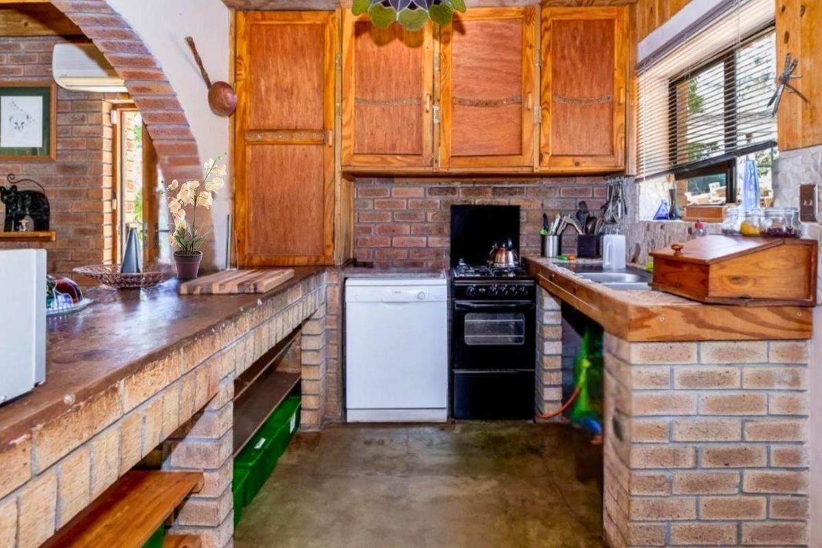 Rustic kitchen featuring exposed brick counters, wooden cabinetry, and a built-in stove, offering a traditional farmhouse aesthetic.