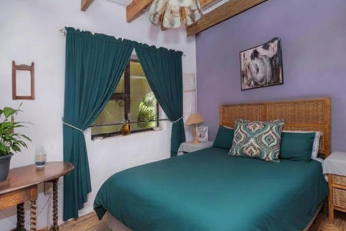 A cozy bedroom featuring exposed timber ceiling beams and a feature wall, providing a rustic and inviting atmosphere.