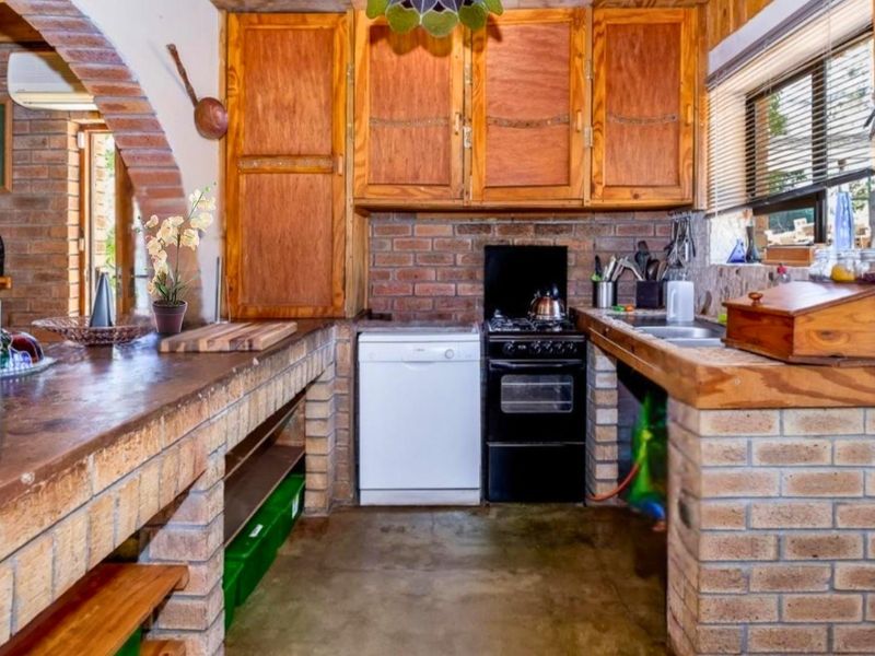 Rustic kitchen featuring exposed brick counters, wooden cabinetry, and a built-in stove, offering a traditional farmhouse aesthetic.