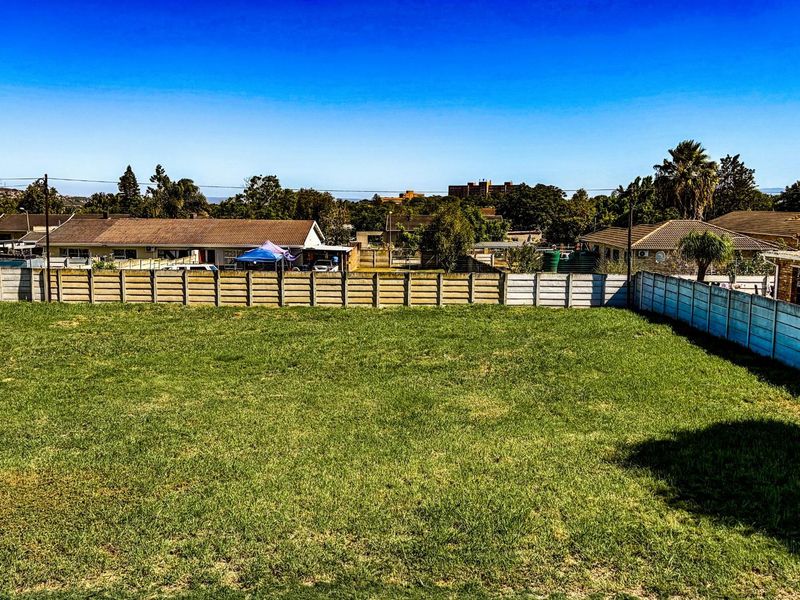 A vacant residential plot featuring a level grassed area enclosed by precast concrete boundary walls, offering a clear space for future development.