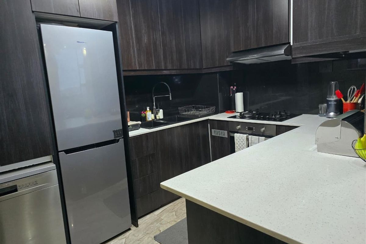 Modern kitchen featuring dark wood cabinetry, stone countertops, integrated oven, gas hob, extractor fan, and a double sink with a contemporary faucet.