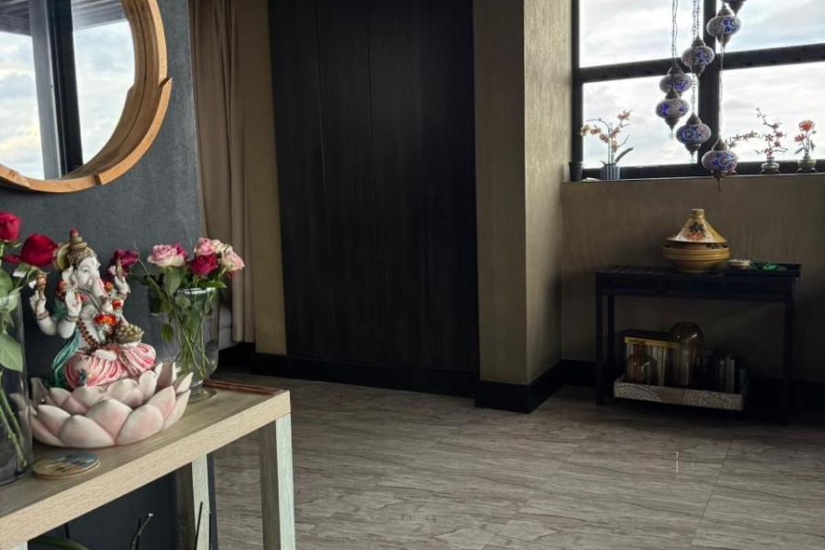 A well-maintained living area featuring polished stone-look floor tiles, dark wood-paneled walls, and a timber-slatted ceiling with recessed lighting.