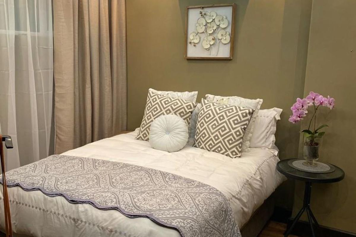 A well-appointed bedroom featuring recessed ceiling lighting, a modern ceiling fan, and a wall-mounted air conditioning unit.