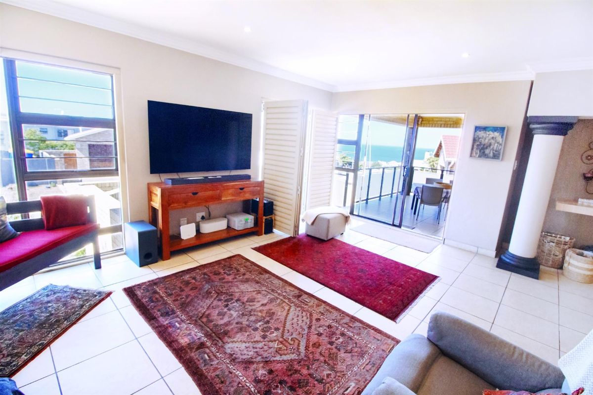 Spacious living room featuring tiled flooring, recessed lighting, and large sliding doors opening onto a balcony with coastal views.