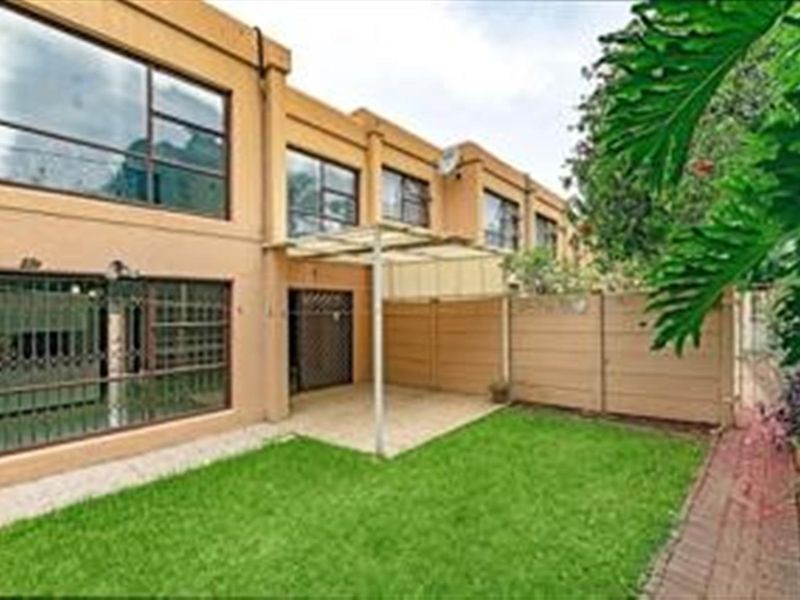 Rear view of the apartment featuring a private garden, paved patio area, and secure access points.