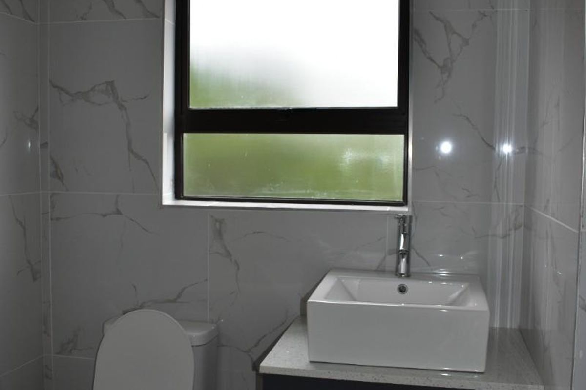 Modern bathroom featuring marble-look wall tiles, a contemporary vessel sink on a dark vanity, and a white toilet.